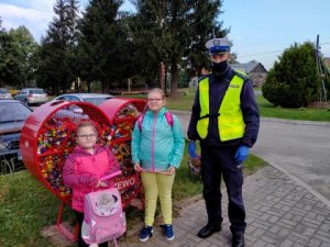 Na zdjęciu policjant Ruchu Drogowego z dziećmi przy szkole w Kraszewie