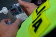 Zdjęcie przedstawia policjanta trzymającego alkomat.