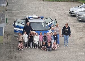 Policjant z dziećmi przy samochodzie policyjnym