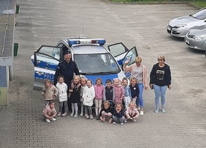 Policjant z dziećmi przy samochodzie policyjnym