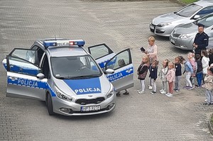 Policjant pokazujący dzieciom samochód policyjny