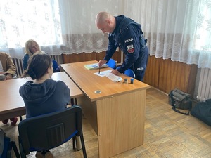 Policjant prezentujący dzieciom technikę zabezpieczenia odcisków palców