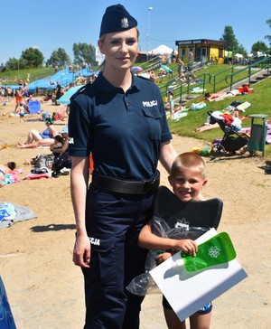 Policjantka z dzieckiem, które otrzymało wakacyjne upominki