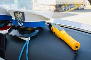 Zdjęcie poglądowe przedstawiające policyjne czapki oraz urządzenie do badania stanu trzeźwości