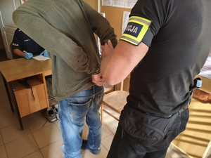 Policjant doprowadzający zatrzymanego.